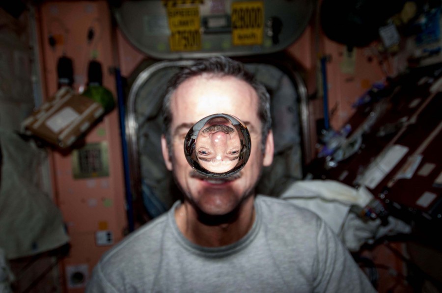 空间站中,哈德菲尔德在镜头前观察悬浮状的水泡,经过水的折射,他的脸