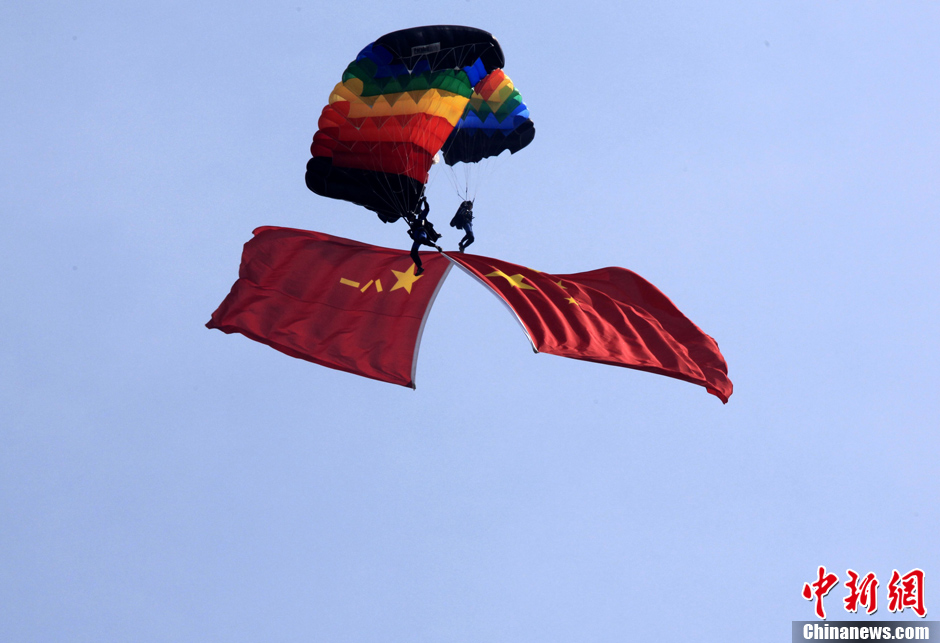 图为两名跳伞队员各持中国国旗和八一军旗在空中演绎擦肩而过